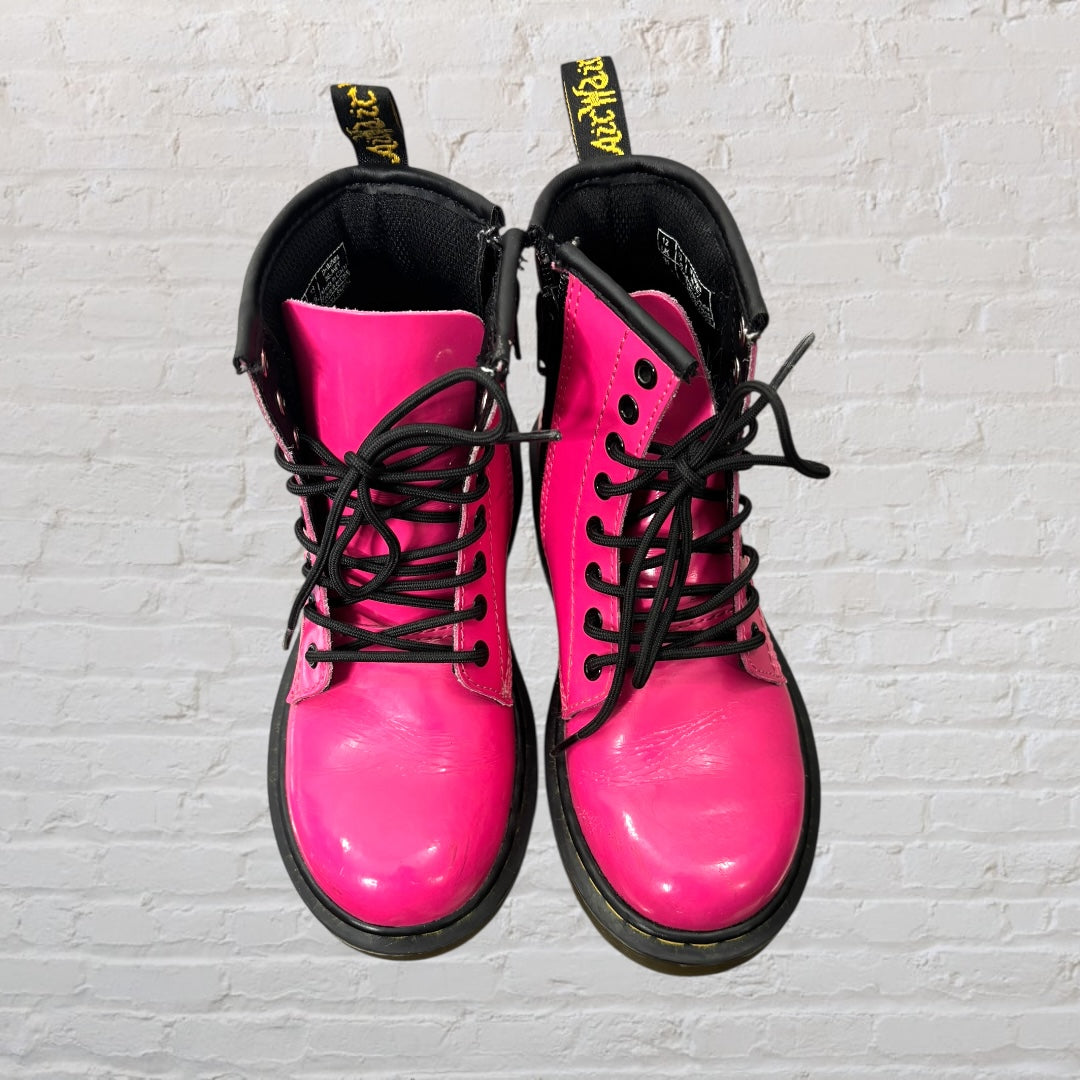 Bright pink lace-up combat boots with black laces and soles, featuring a pull tab at the back.