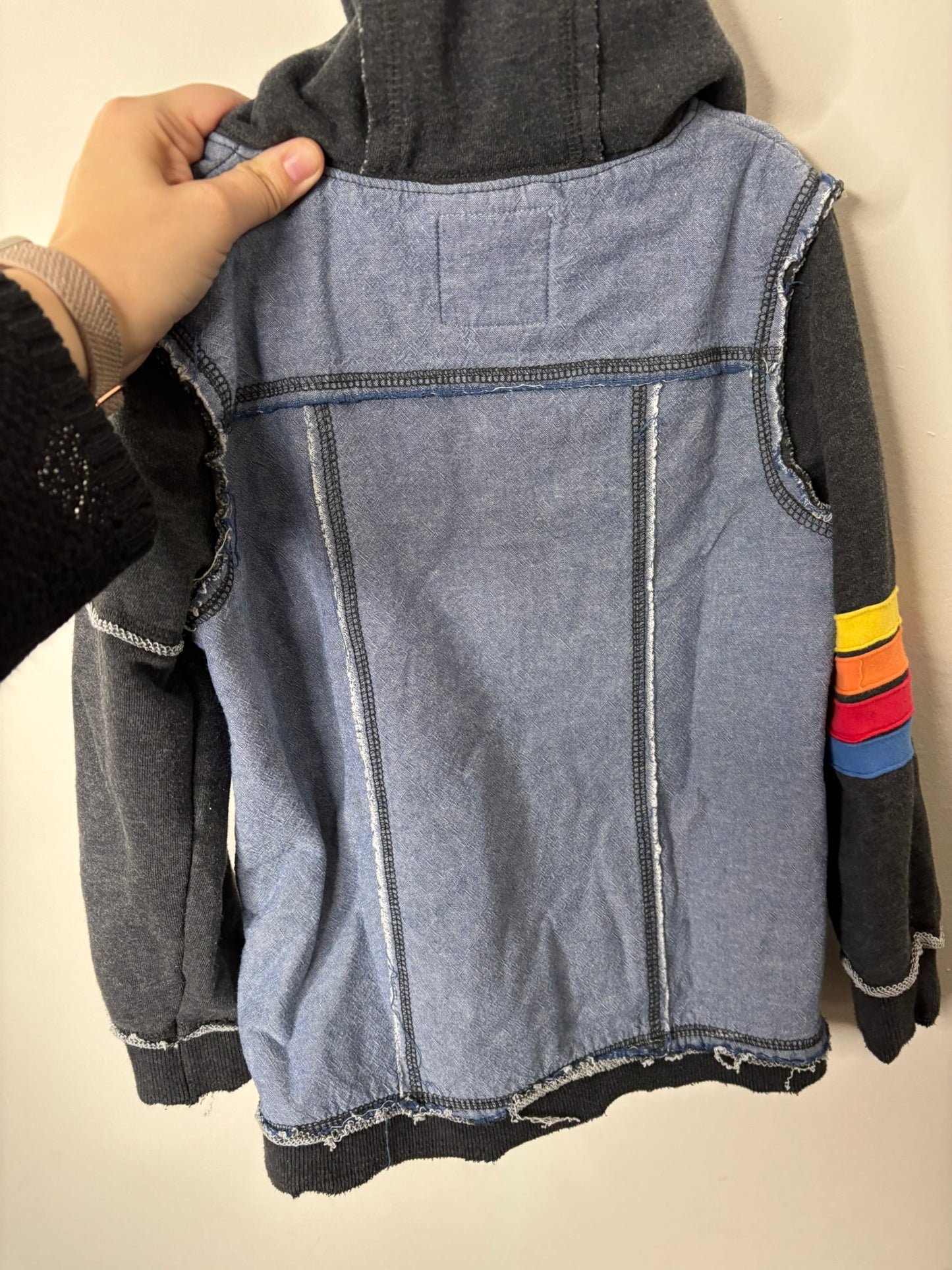 Black hoodie with denim-style print and colorful stripes on the sleeve, featuring a red lining and zip closure.