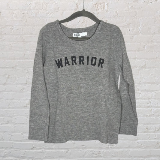 Grey long sleeve shirt with 'WARRIOR' text across the front, hanging on a hanger.