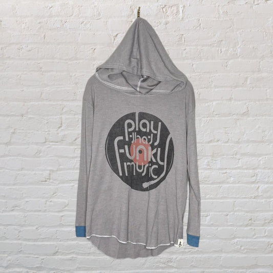 Gray hoodie with 'Play That Funky Music' graphic on front, featuring a hood and long sleeves, hanging against a brick wall.
