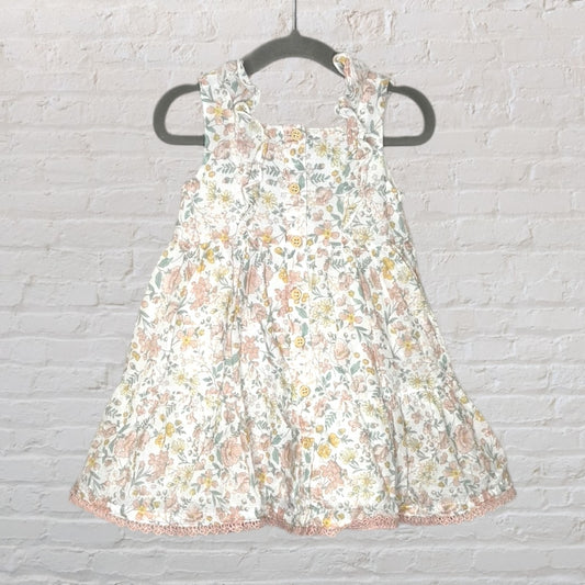 White sleeveless dress with multicolour floral pattern and button-up front, hanging on a dark hanger.