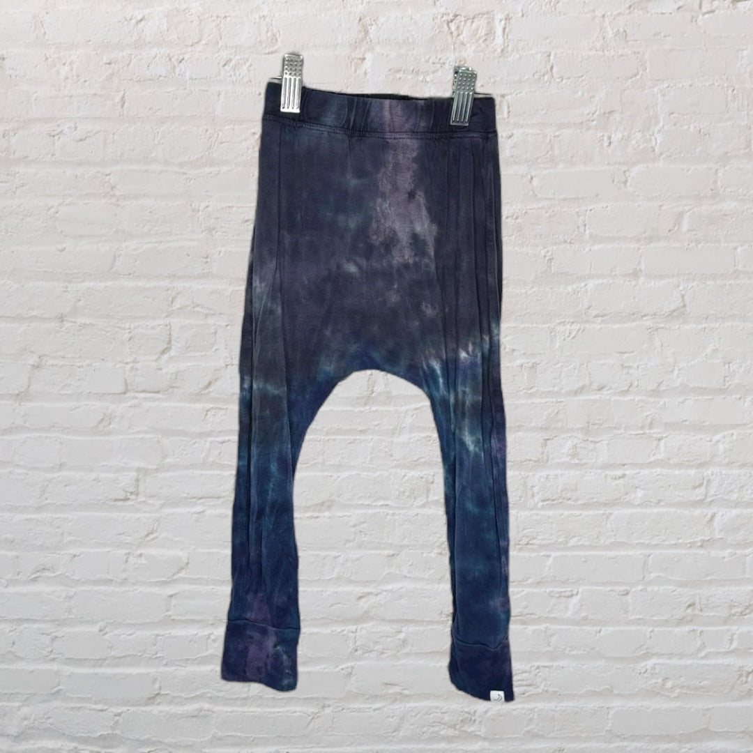 Dark blue and purple tie-dye drop crotch leggings hanging against a white brick wall.