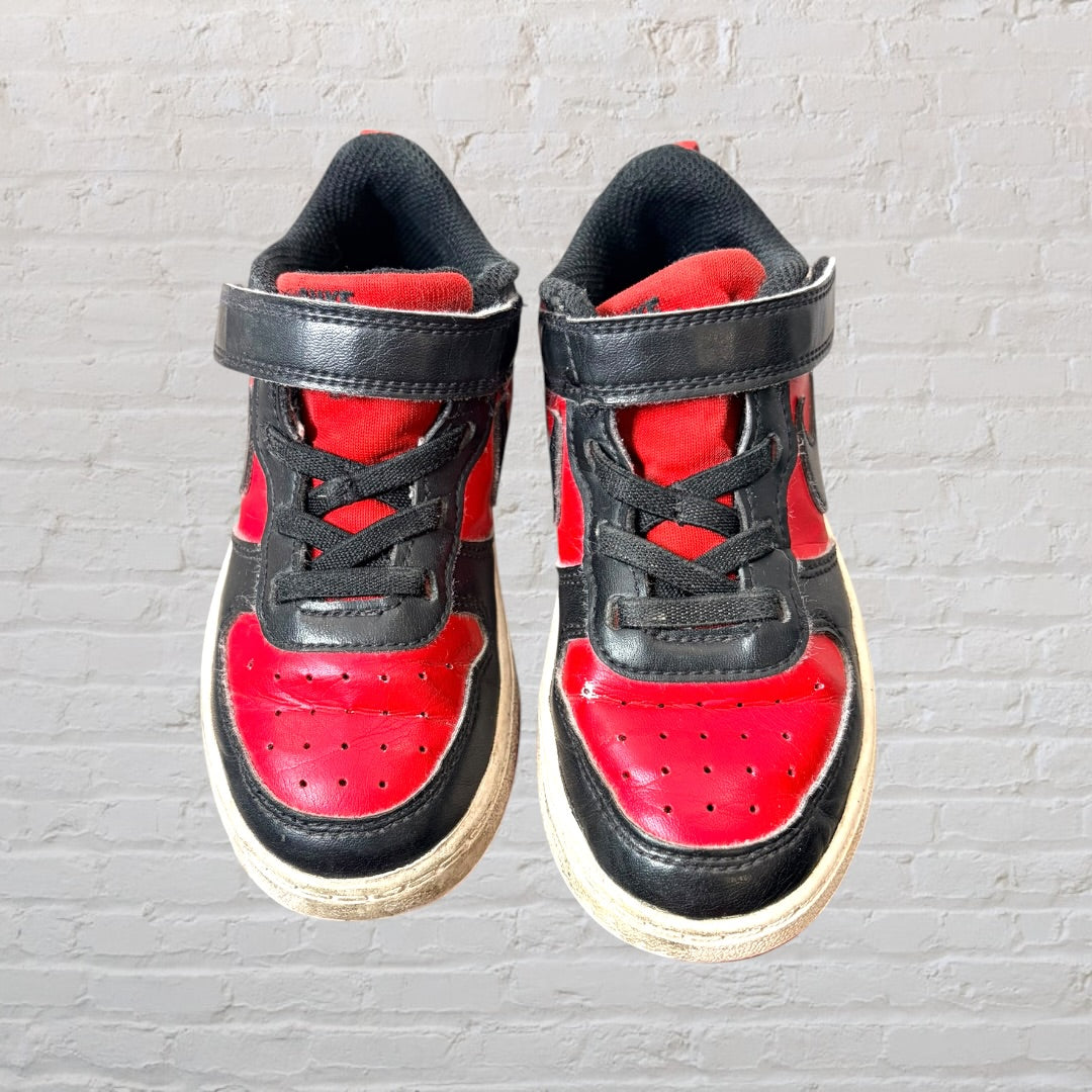 Pair of red and black low-top Nike sneakers with visible wear, Velcro straps, and laces.