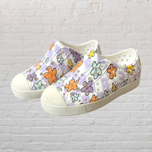 Stylish slip-on shoes with a pastel floral pattern featuring lilac, orange, mint, and yellow on a white base.