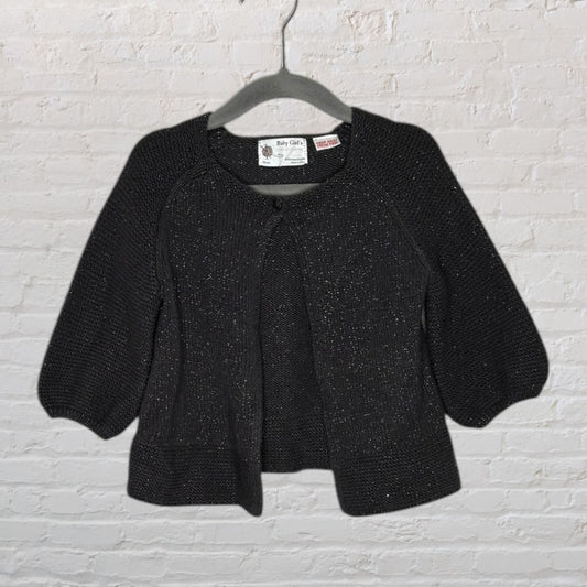 Black knitted girl's cardigan with button closure and three-quarter sleeves, displayed on a hanger.