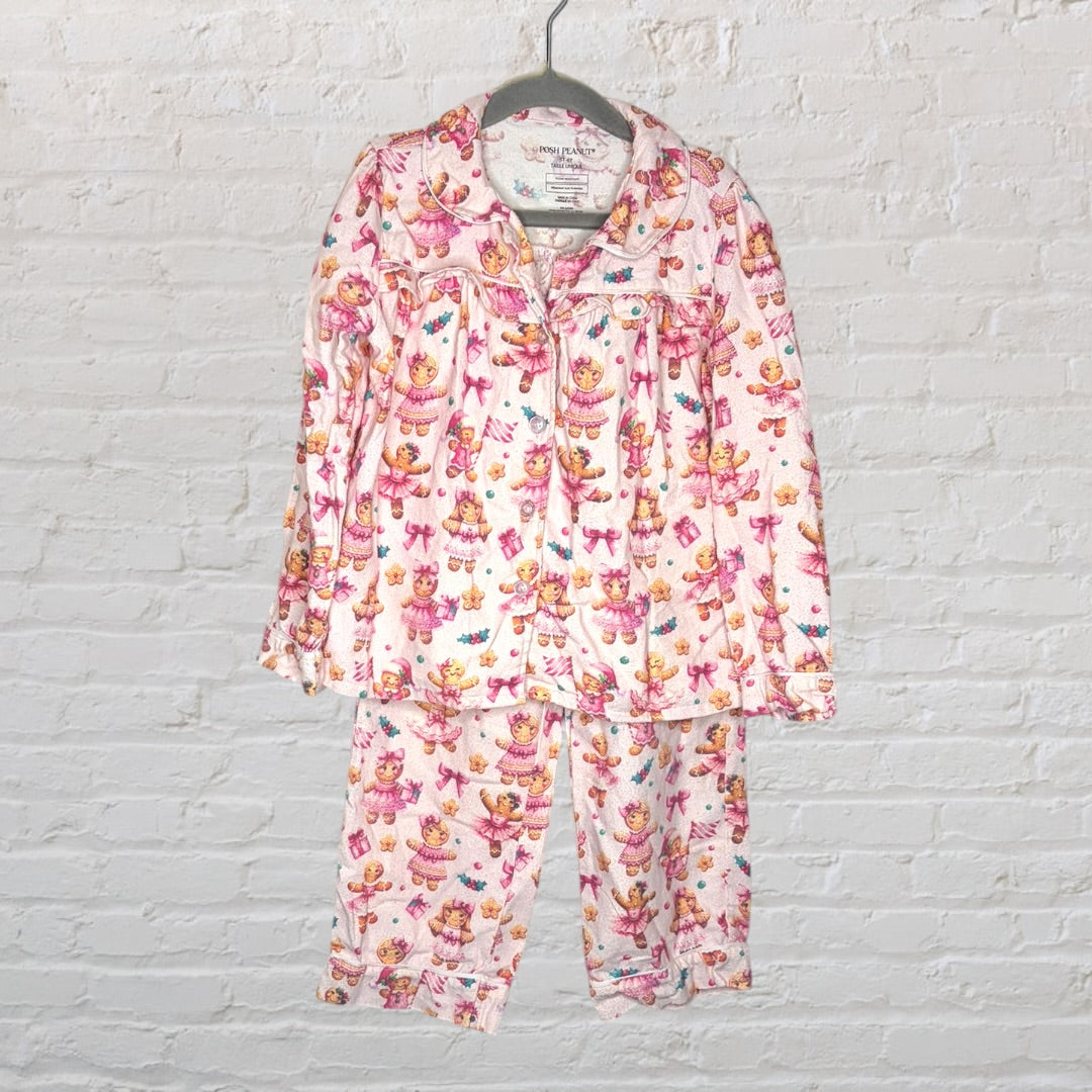 Pink pajama set with bear and bow print, featuring a button-up top and pants, hanging on a hanger.