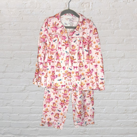 Pink pajama set with bear and bow print, featuring a button-up top and pants, hanging on a hanger.