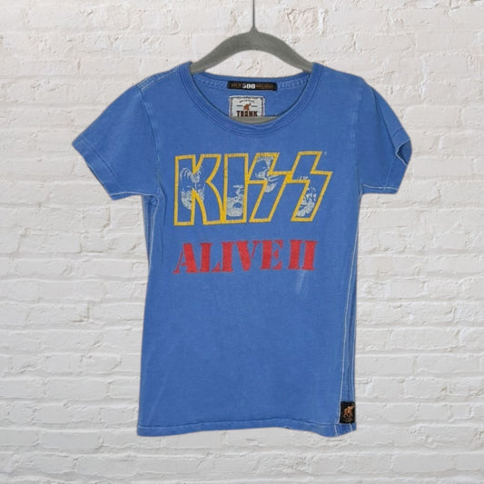 Blue t-shirt with 'KISS Alive II' faded graphic, hanging on a hanger against a white brick wall.
