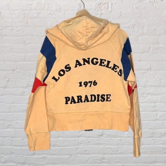 Beige hoodie with 'Los Angeles 1976 Paradise' text and red and blue accents on the sleeves.