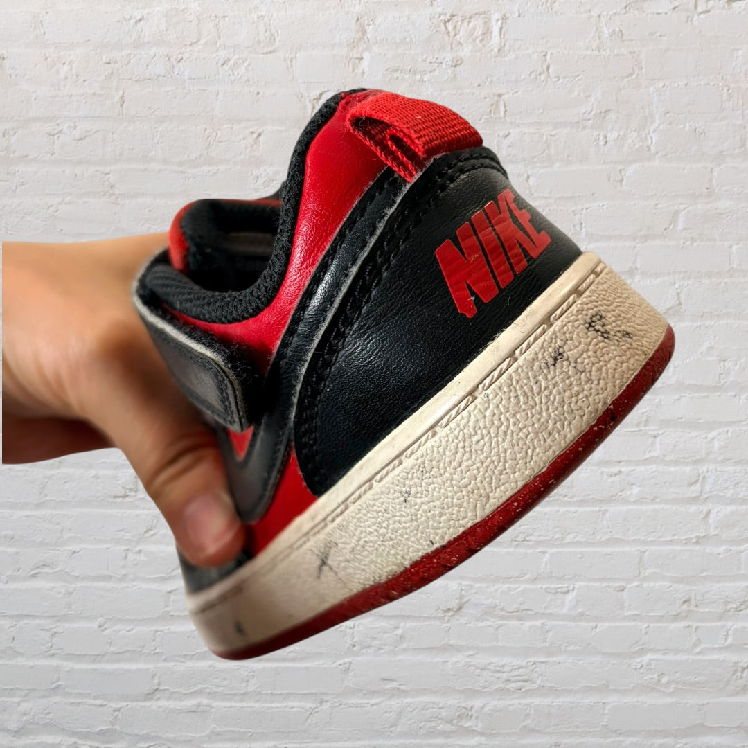 Pair of red and black low-top Nike sneakers with visible wear, Velcro straps, and laces.