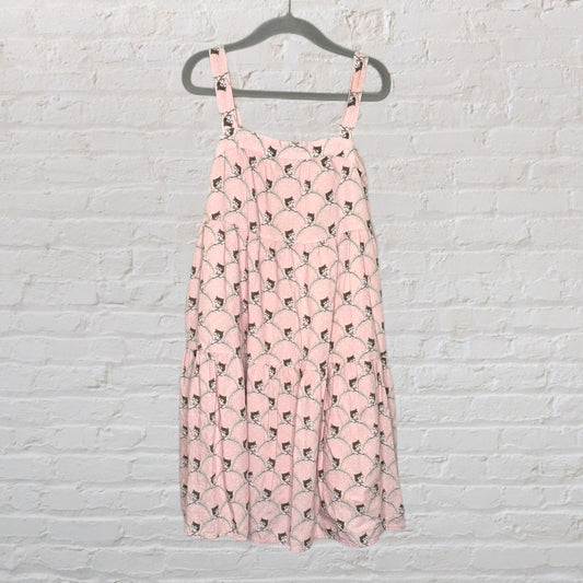 Pink sleeveless dress with a playful cat print and tiered design, hanging on a hanger.