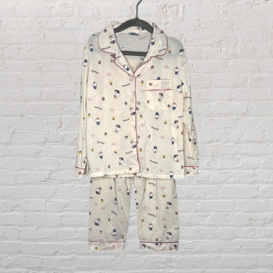 Cream pajama set with cartoon prints, featuring a button-up top and matching pants, displayed on hanger.