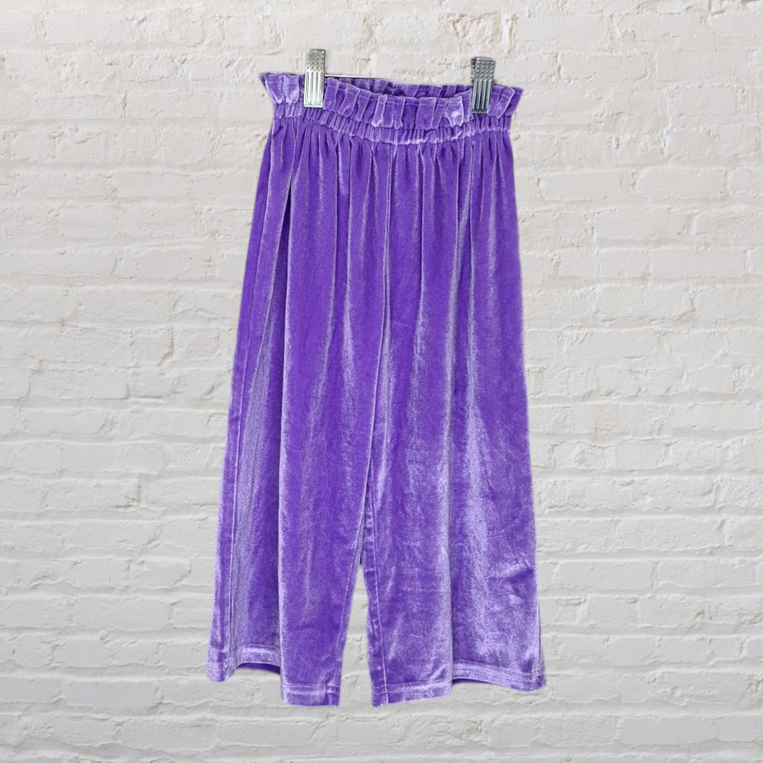 Lavender velvet high-waisted pants with an elastic waistband displayed against a white brick background.