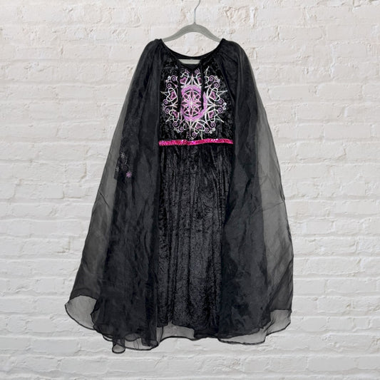 A black velvet dress with a cape, adorned with pink embroidery and a glittery pink sash.