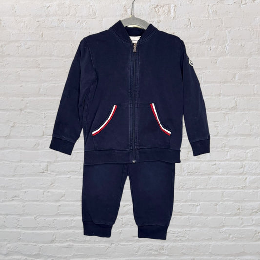 Navy blue Moncler kids' track suit with zip-up jacket and matching pants, featuring red, white, and blue trim detail on pockets.