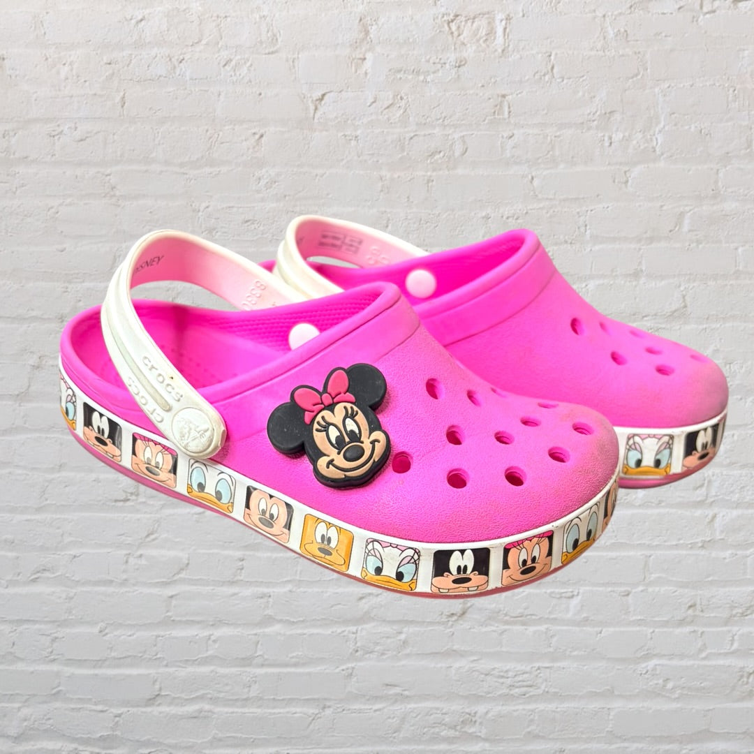 Pink Crocs clogs with Minnie Mouse design and Disney character print on the sole, featuring adjustable heel strap.