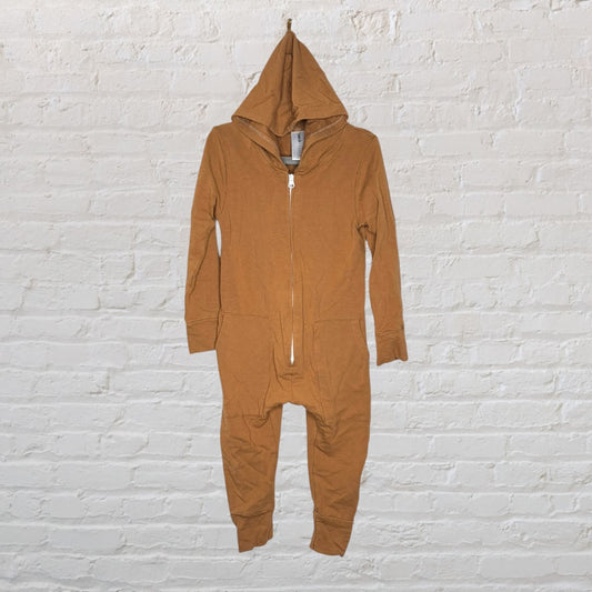 Brown hooded onepiece with a front zipper, designed for comfort, hangs against a white brick wall.