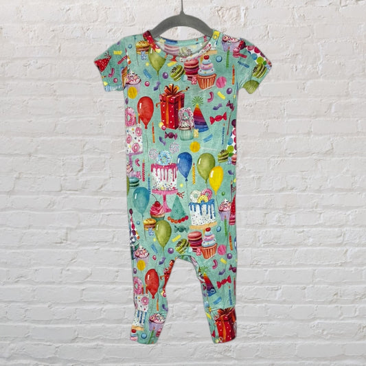 A colorful baby romper with a festive birthday theme featuring cakes, balloons, and gift prints.