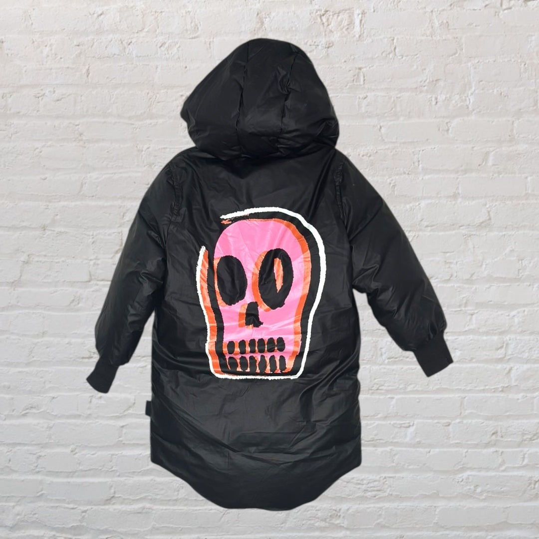 Black hooded puffer jacket featuring a large pink skull graphic on the back, hung against a brick wall background.