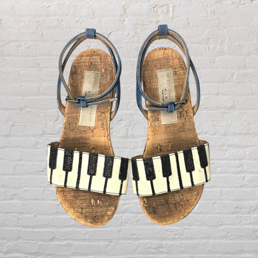Cork sandals with black and white piano key strap and blue adjustable ankle straps.