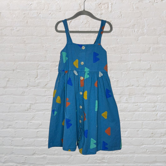 Blue sundress with shoulder straps and colorful geometric shapes, featuring a button-front design, hanging on a black hanger.