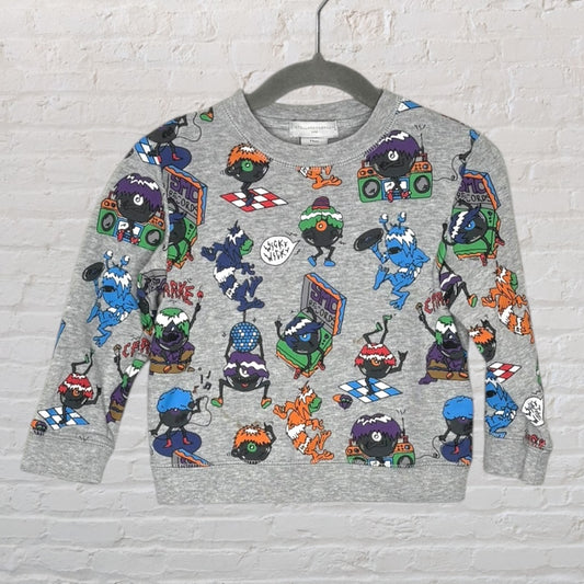 A grey sweatshirt featuring a fun, colorful print of quirky monsters playing instruments and dancing.