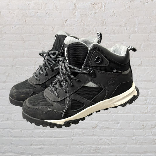 Black and grey high-top hiking boots by Timberland, with sturdy laces and rugged soles.