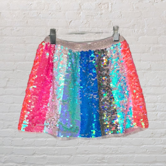 Vibrant multicolor sequin skirt with a shimmer effect on a hanger against a white brick wall.