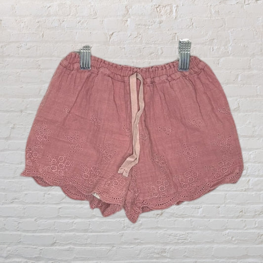 Dusty pink shorts with an elastic waistband and embroidered eyelet hem, displayed on a hanger.