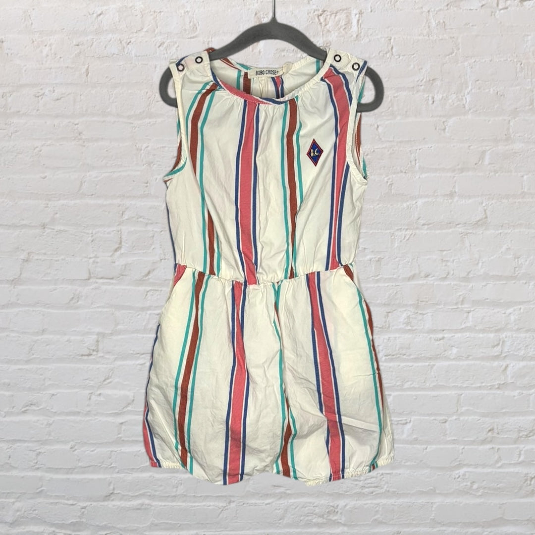 Sleeveless romper with colorful vertical stripes and button details on the shoulders, hanging on a dark hanger.