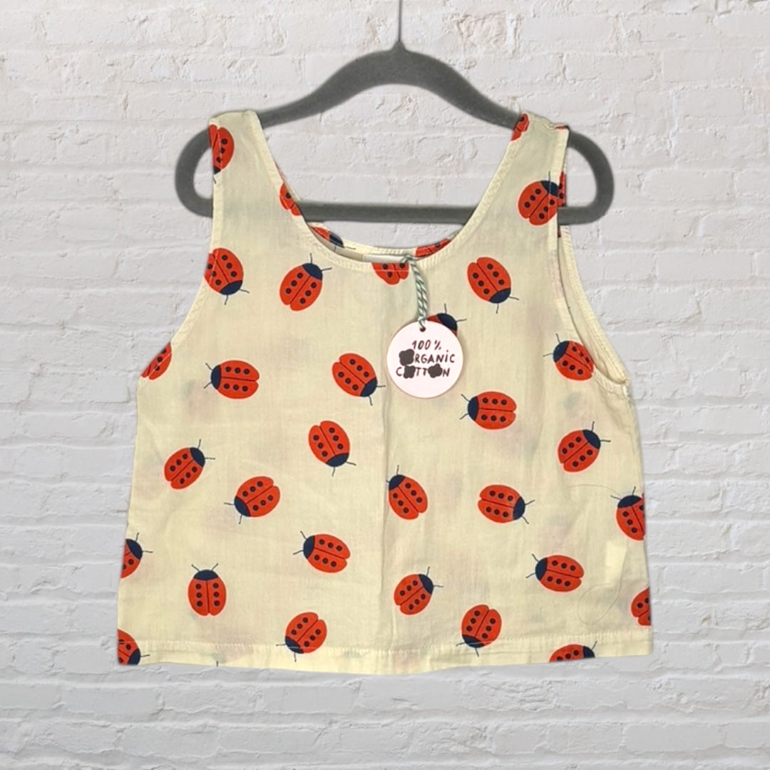 Beige tank top with red ladybug print pattern, made of 100% organic cotton, displayed on a hanger.
