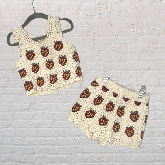Crochet set including a sleeveless top and shorts with strawberry motifs in cream, red, and green.