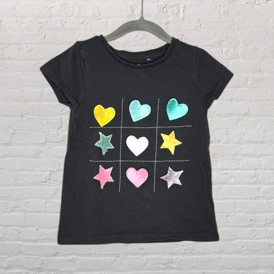 Black T-shirt featuring a tic-tac-toe design with colorful hearts and stars.