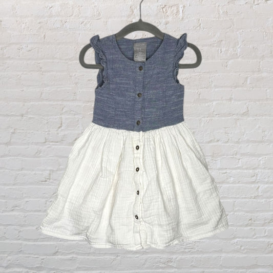 Navy and white sleeveless dress with button-front and ruffled shoulders, hanging on a dark hanger.