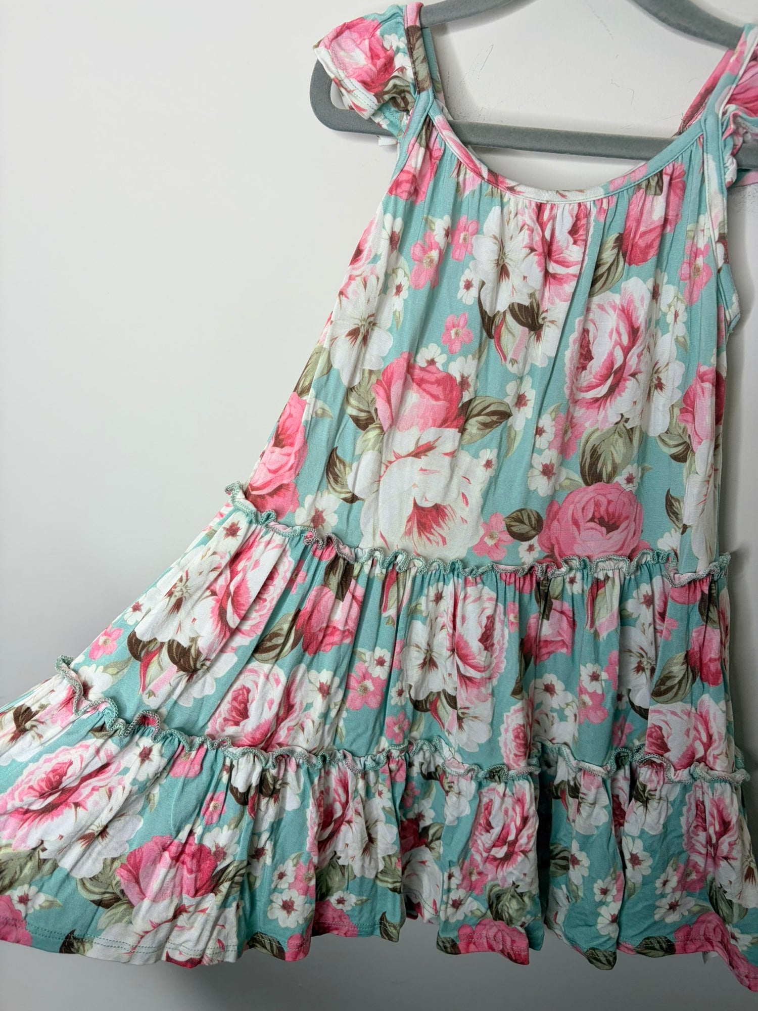 Mint green floral summer dress with pink and white flowers, featuring tie sleeves, hanging on a gray hanger.