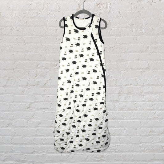 White sleep sack with a black sheep and fence pattern, trimmed in black, hanging on a hanger.