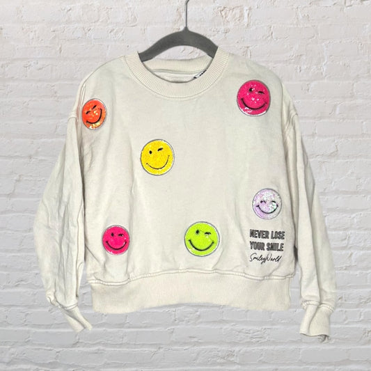 Off-white sweatshirt with multicolored embroidered smiley faces and 'Never Lose Your Smile' text.