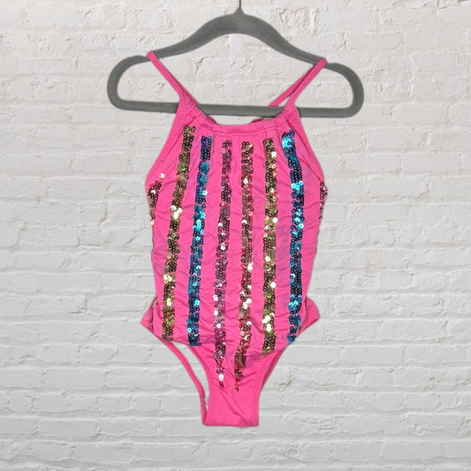 Pink swimsuit with vertical multicoloured sequin stripes, hanging on a hanger.