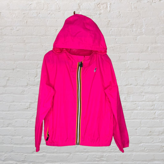 Bright pink hooded windbreaker with a striped zipper, against a white brick background.