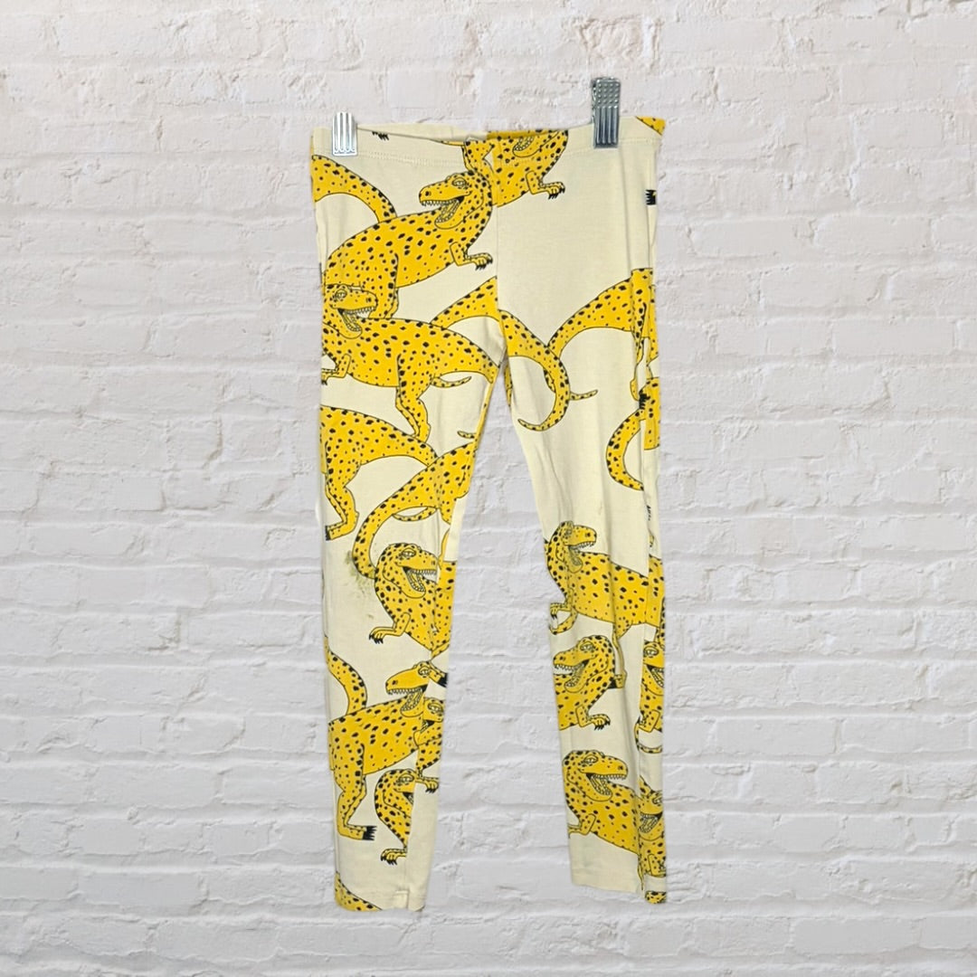 Yellow leggings with black leopard print, hanging against a white brick background.