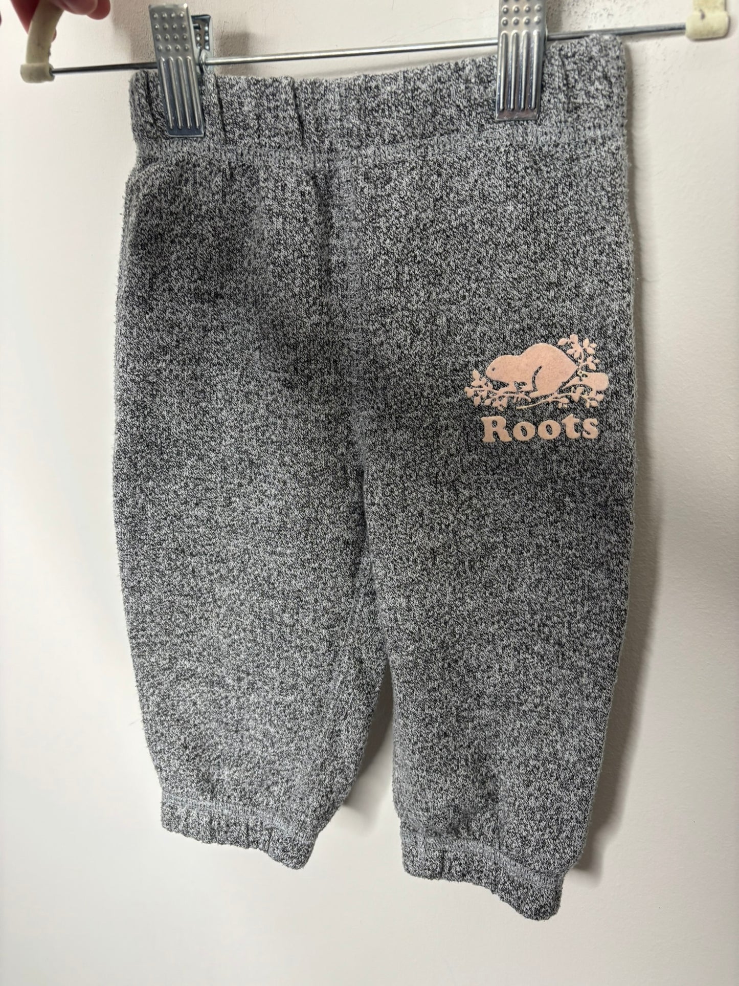 Heather grey Roots hoodie and pants set for kids with logo on the chest, displayed against a brick wall.