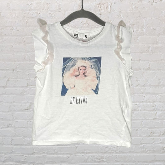 White children's tee with ruffle sleeves and a graphic print of a doll with 'Be Extra' text.