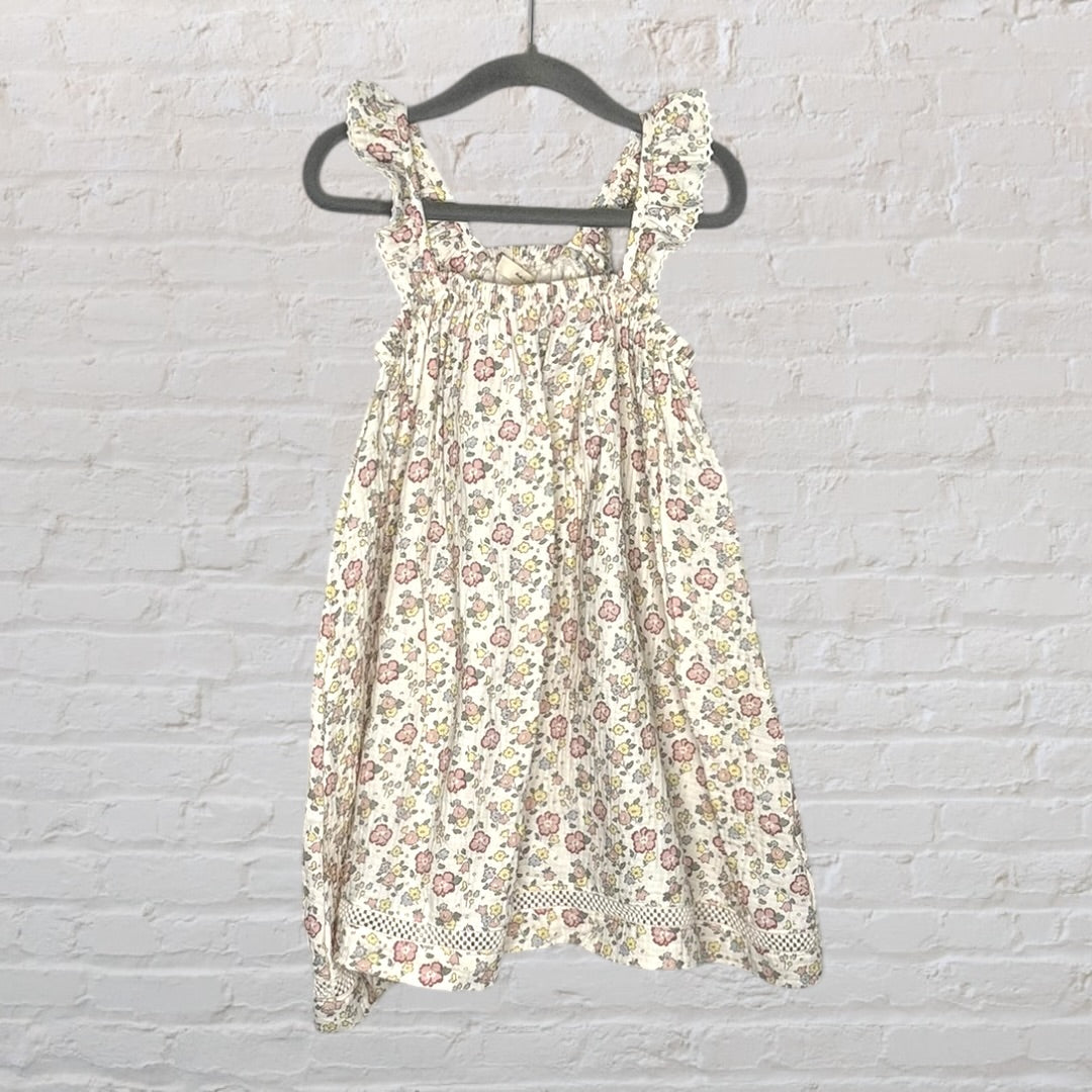 Cream floral dress with ruffle straps and lace trim, featuring pink and yellow flowers, hanging on a hanger.
