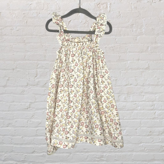 Cream floral dress with ruffle straps and lace trim, featuring pink and yellow flowers, hanging on a hanger.
