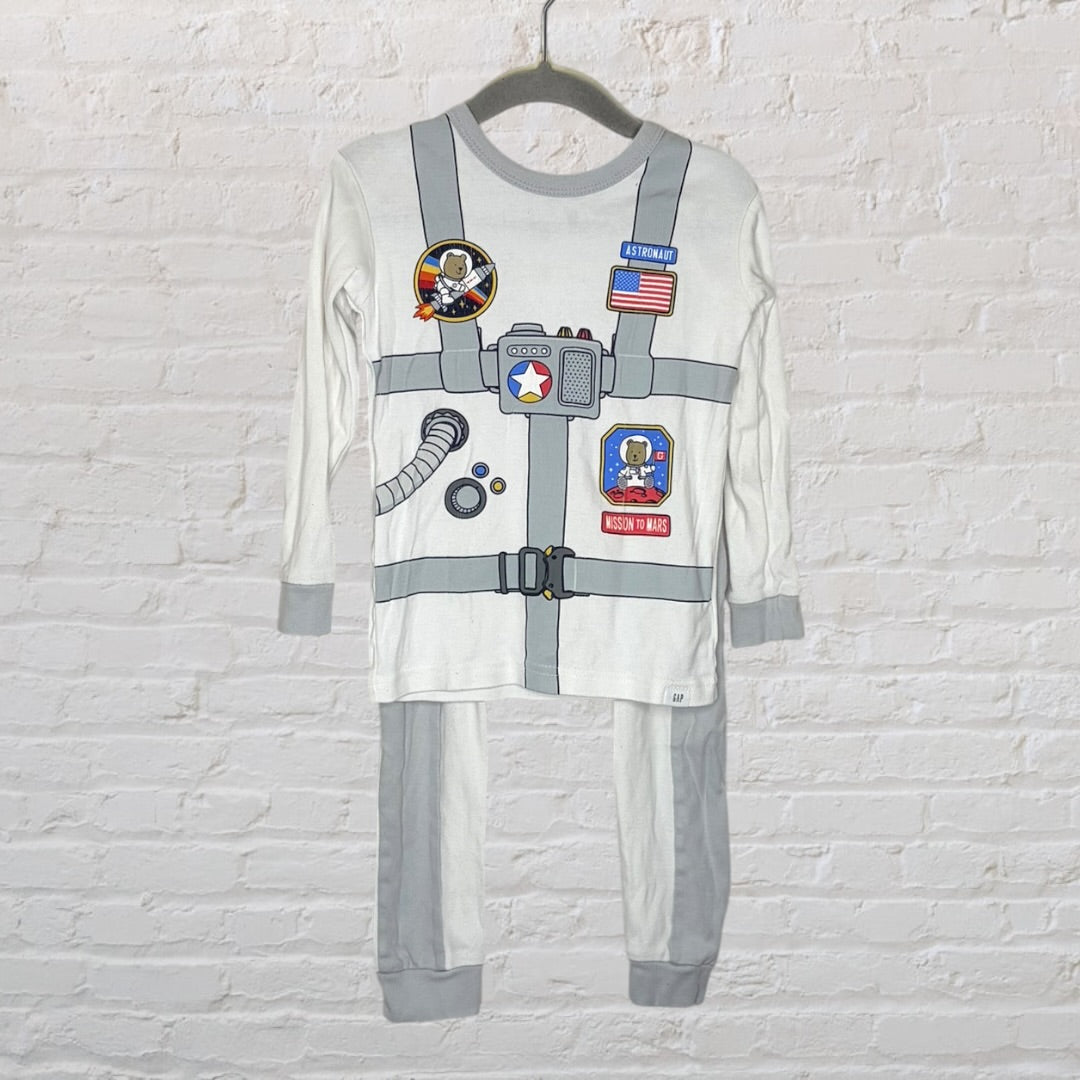 Children's astronaut-themed pajama set with space suit graphic, featuring patches and badges, hanging on a hanger.
