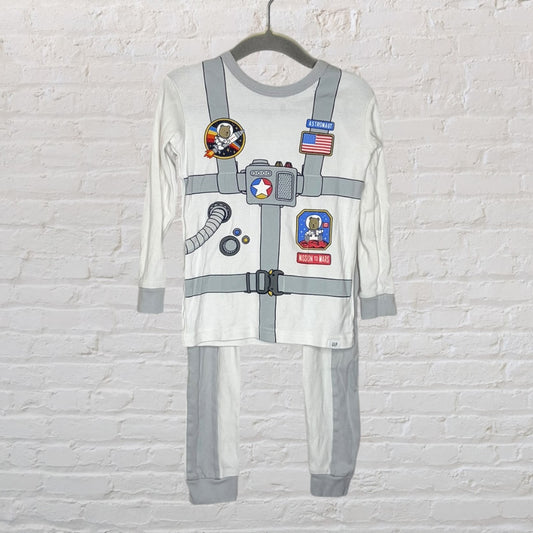 Children's astronaut-themed pajama set with space suit graphic, featuring patches and badges, hanging on a hanger.