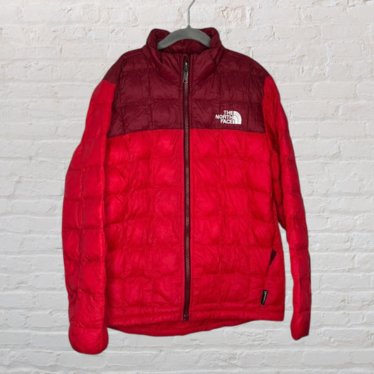 Red and burgundy quilted jacket from The North Face with a full zip and logo on the chest.
