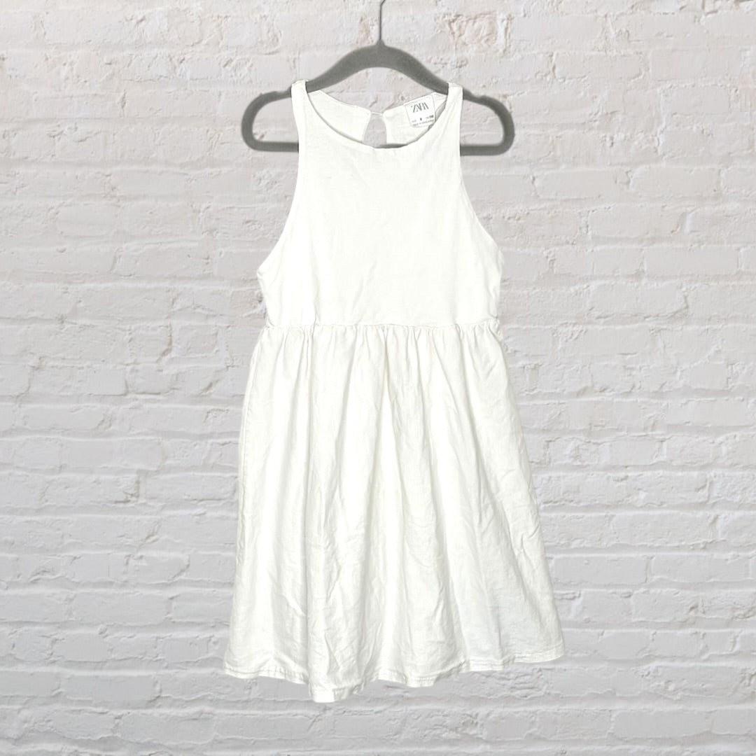 White sleeveless midi dress from Zara, displayed on a hanger against a white brick background.