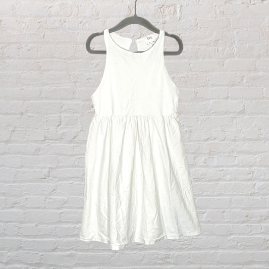 White sleeveless midi dress from Zara, displayed on a hanger against a white brick background.