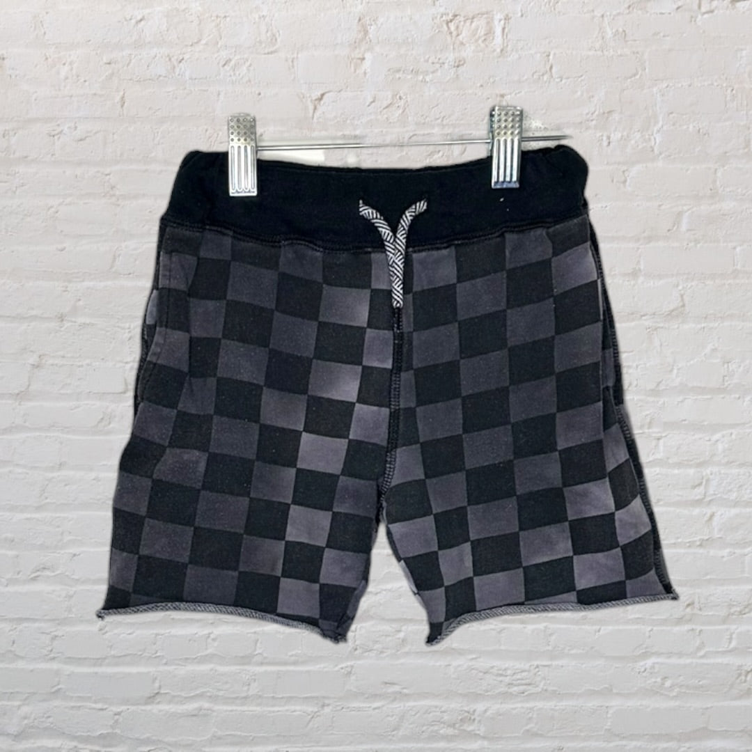 Black and grey checkered shorts with a drawstring waistband hanging on a hanger.